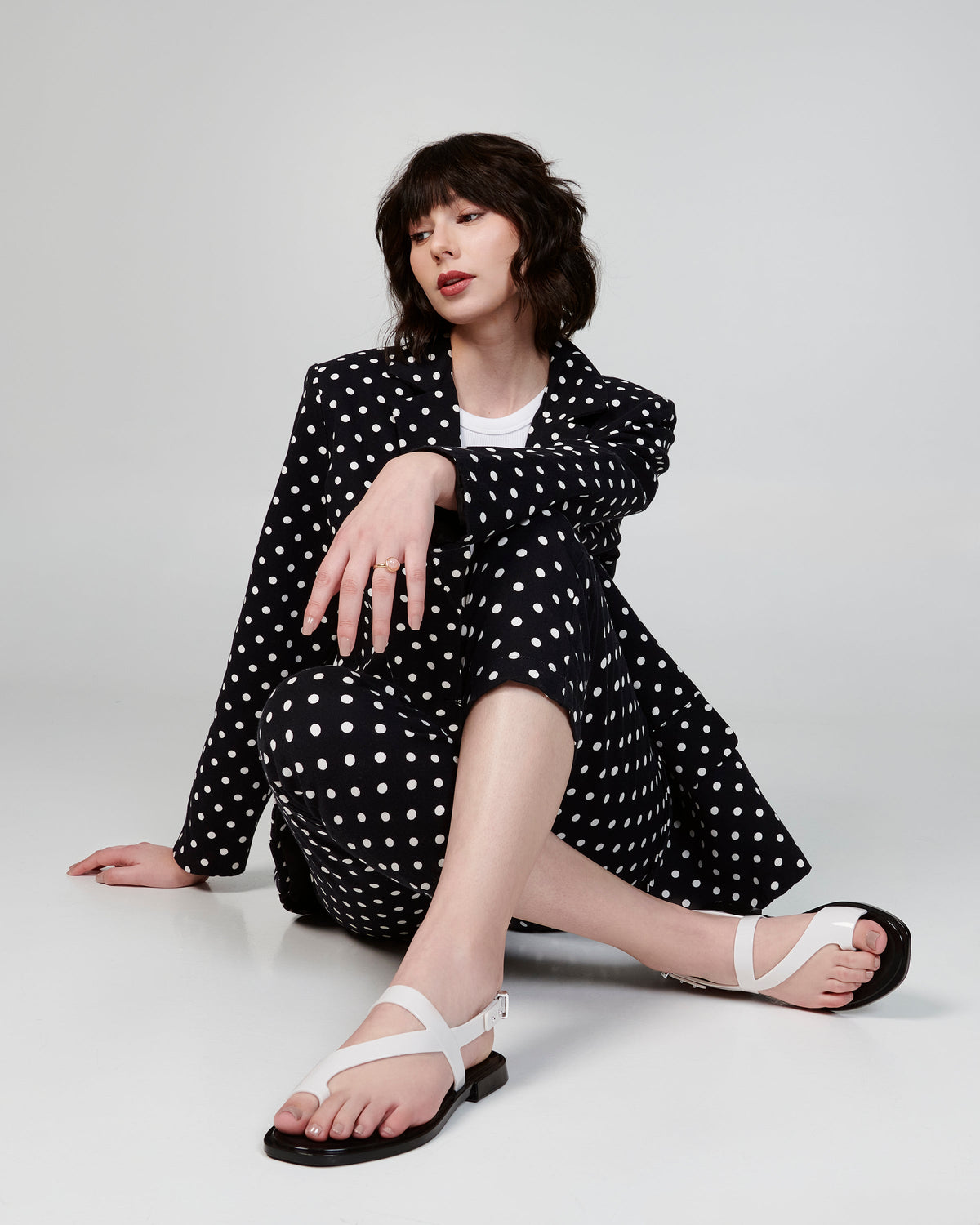 Model wearing a polka dot suit wearing a pair of white Cassie sandals.