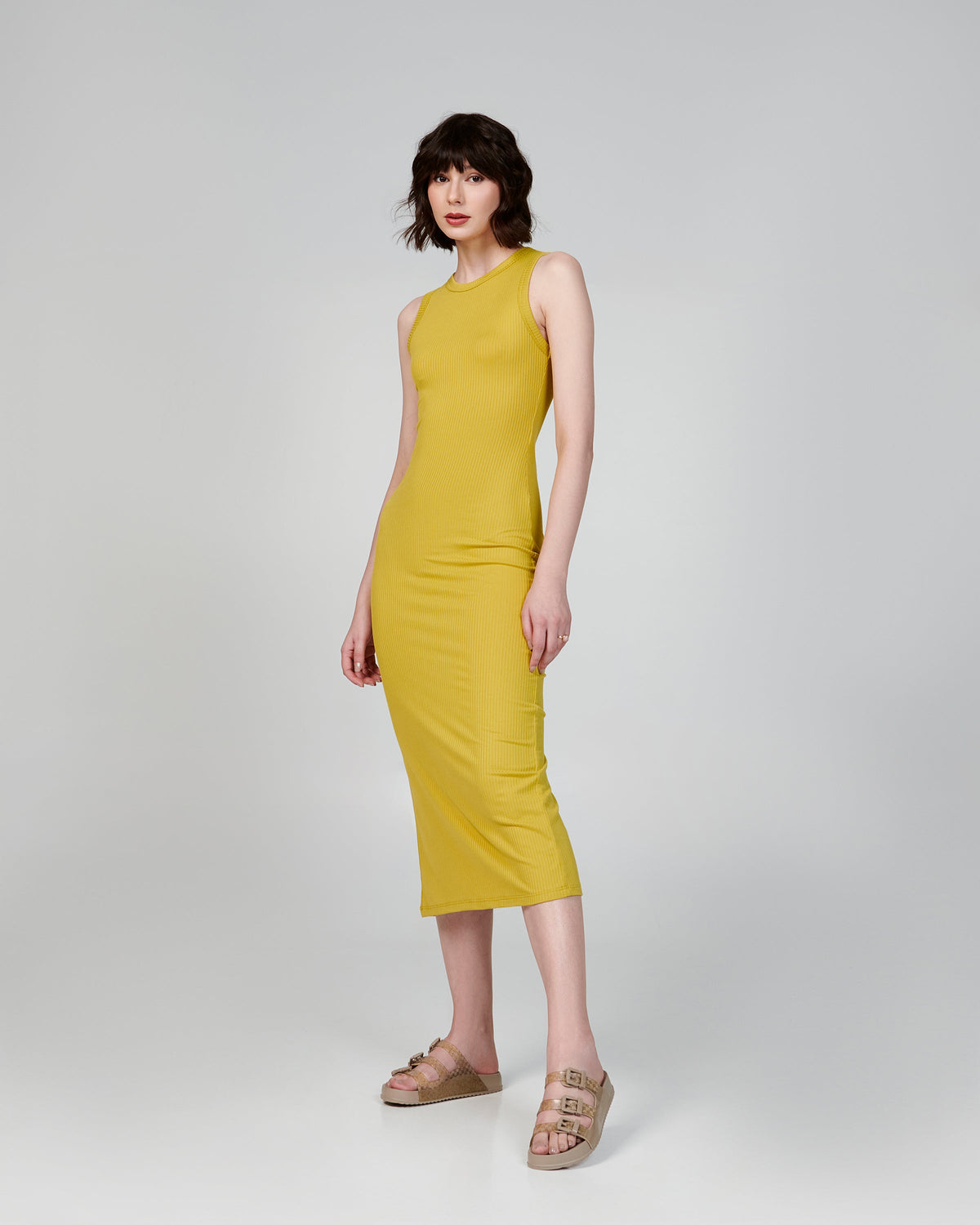 Model in a yellow dress wearing a pair of beige Cozy Stripes slides