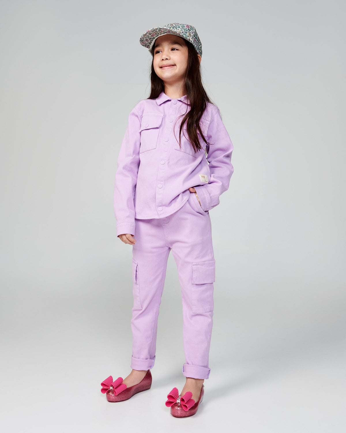 Child model in a purple outfit wearing a pair of glitter pink kids Ultragirl Classic Bow kids flats