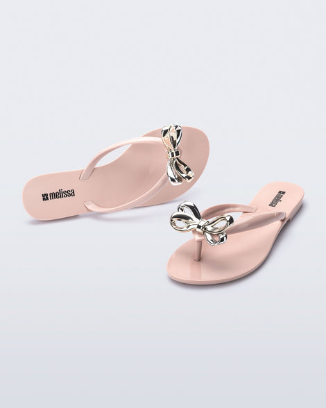 Top and angled view of a pair of pink Harmonic Eclipse flip flops with bow.
