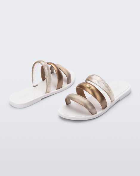 Back and angled view of a pair of white Eclipse Slides with bronze straps.