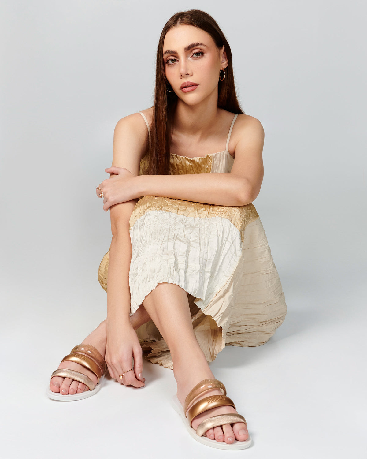 Model in a beige dress wearing a pair of white Eclipse Slides.