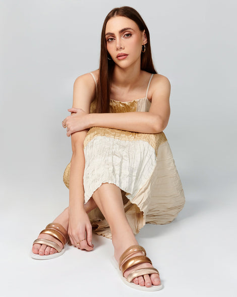 Model in a beige dress wearing a pair of white Eclipse Slides.