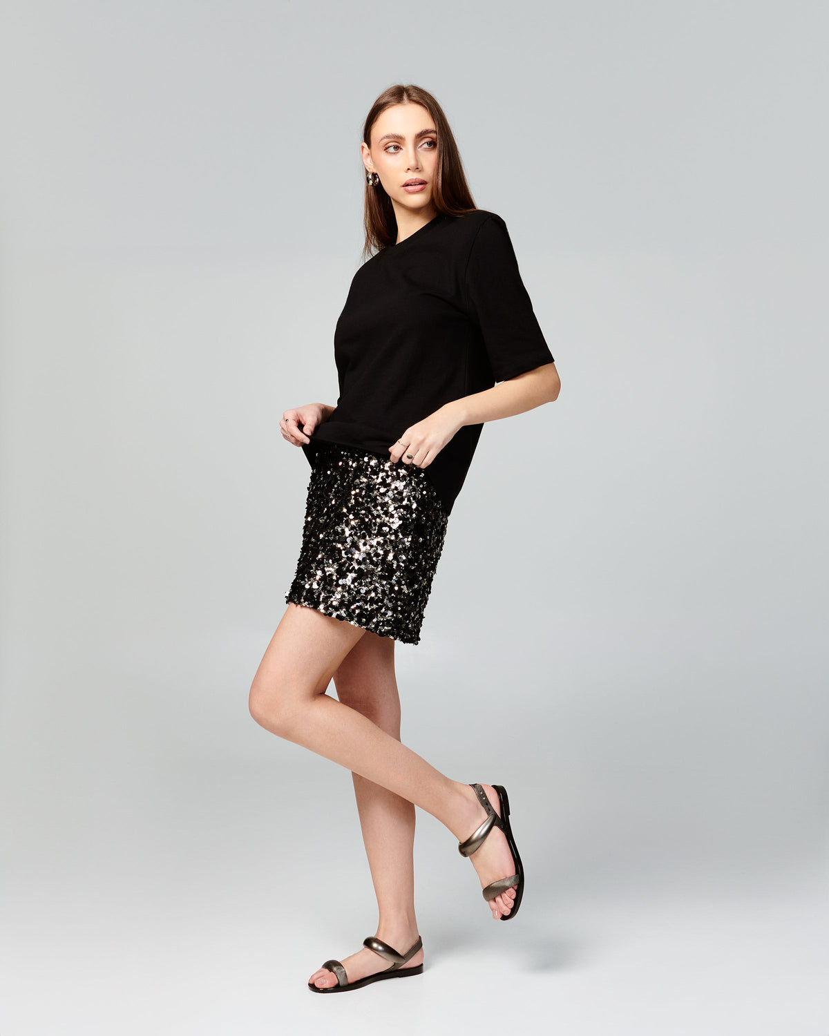 Model in black shirt and sparkly skirt wearing a pair of black Eclipse Sandals with silver straps.