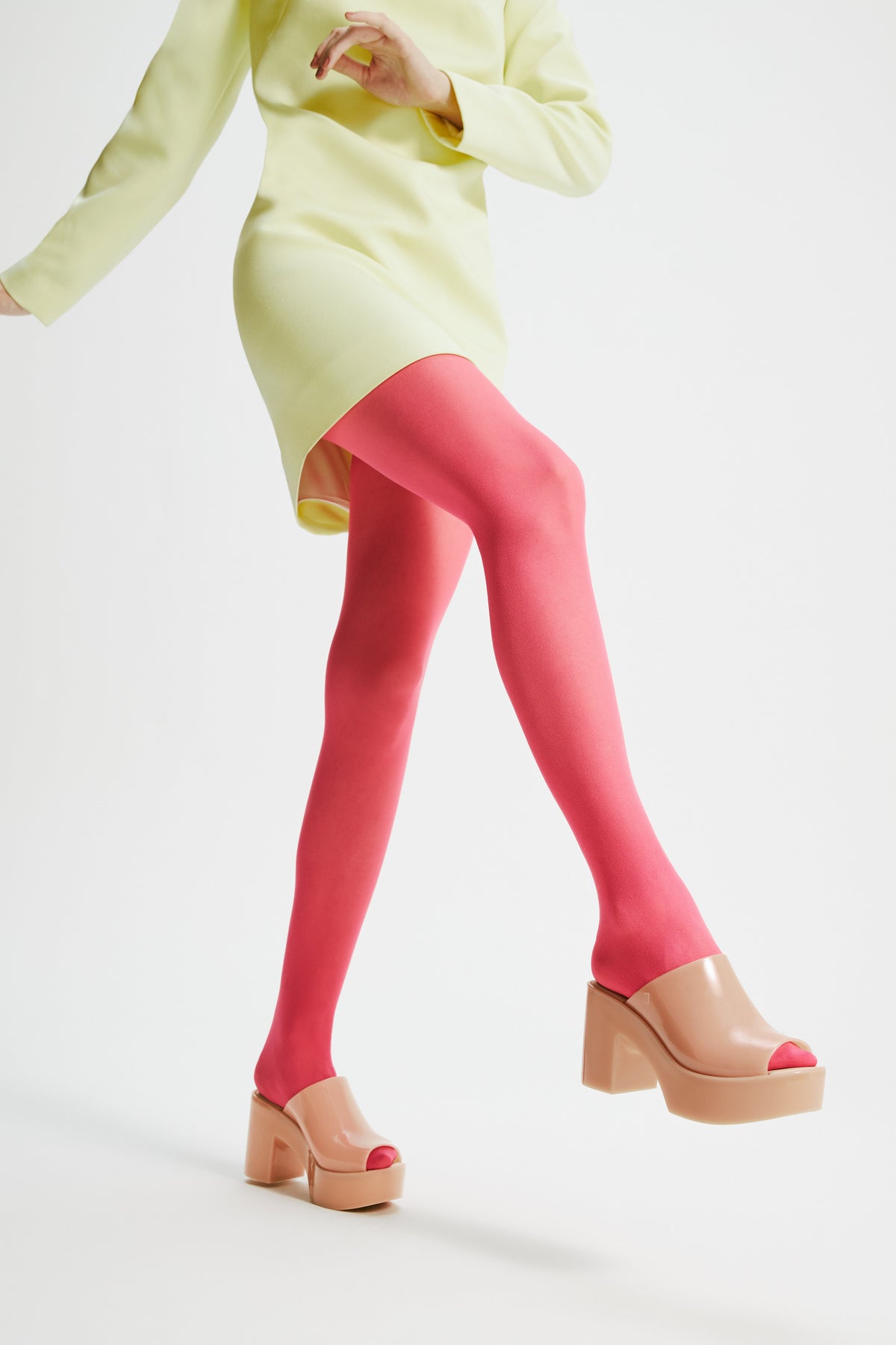 Model in a yellow dress and pink tights wearing a pair of beige Mule Hype platforms.