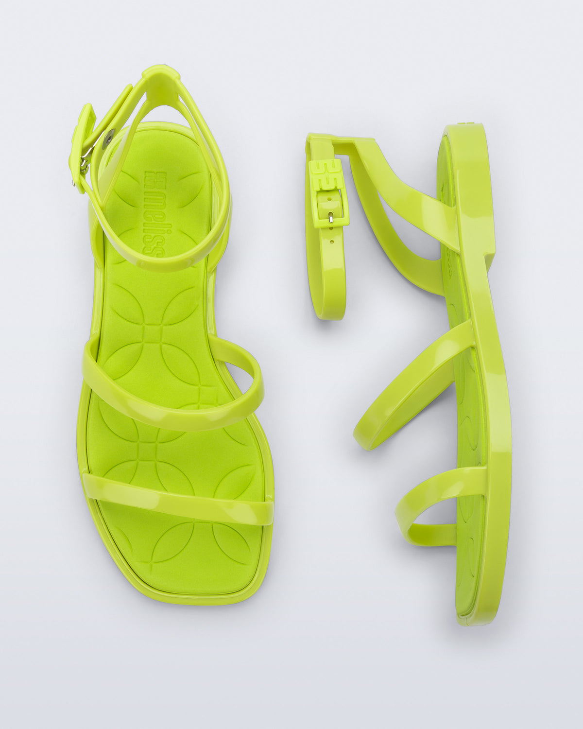 Top and side view of a pair of Melissa Heat neon green sandals on a light gray background