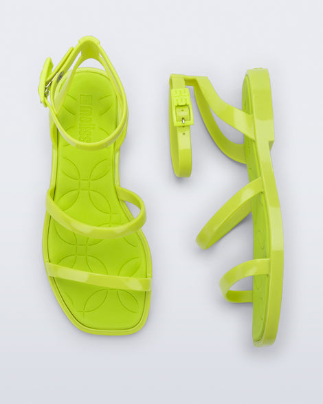 Top and side view of a pair of Melissa Heat neon green sandals on a light gray background