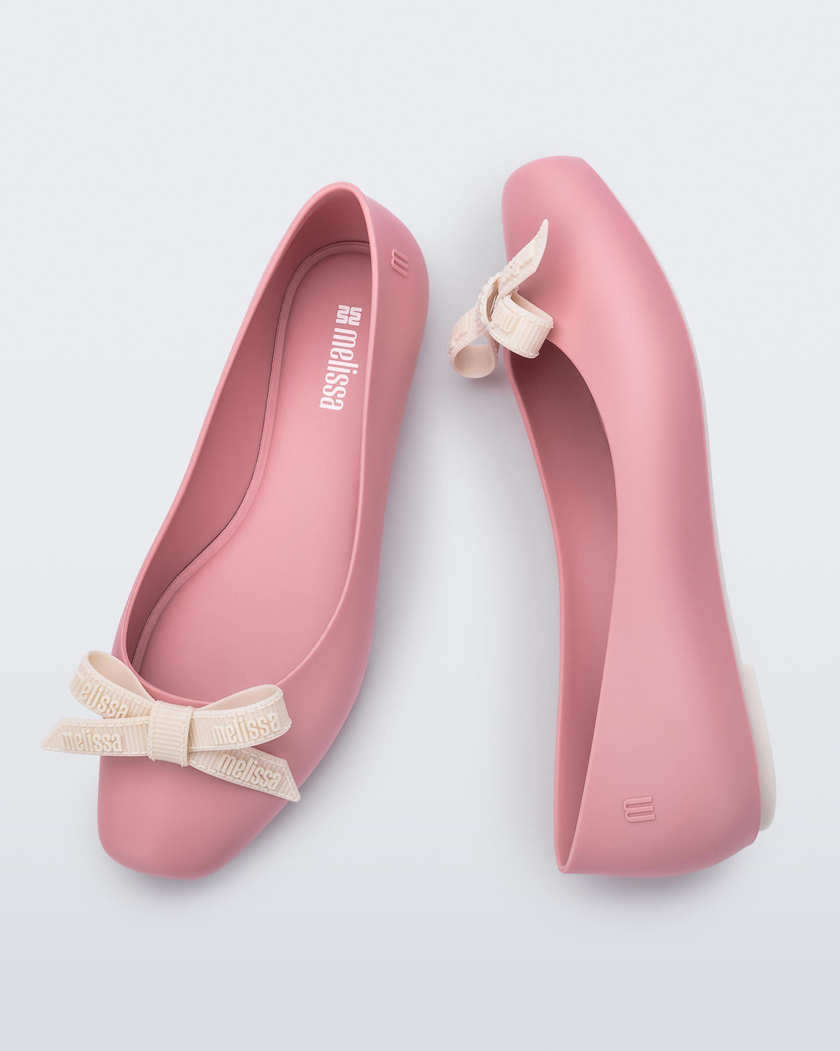 Top and side view of the Melissa Aura flats in pink with  beige bow details on a light gray background