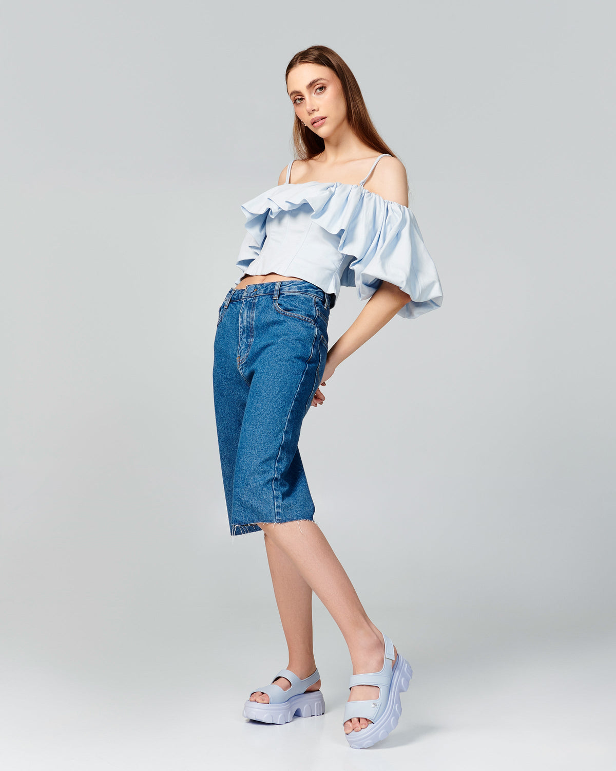 Model in cutoff jeans and shirt wearing a pair of blue Ella Move platform sandals.