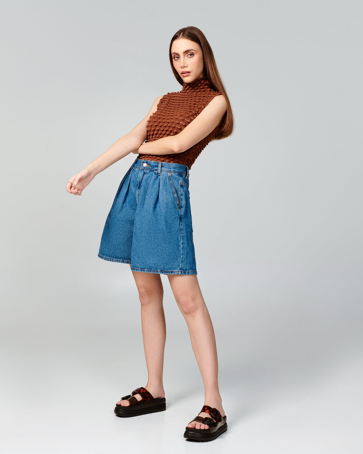 Model in jean shorts and brown shirt wearing a pair of black Cozy Platform sandals with tortoise color straps