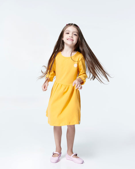 Child model in a yellow dress wearing a pair of pink Soft Ballerina kids flats
