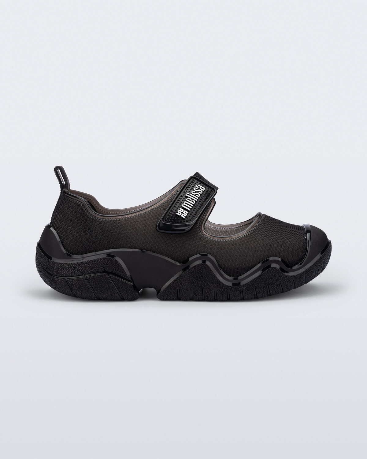 Side view of the Melissa Sprint Ballerina flat in black  velcro strap on a light gray background
