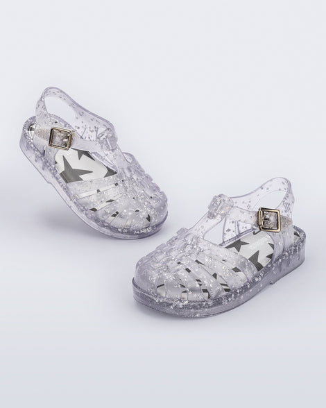 Angled view of a pair of clear Possession baby sandals with star glitter