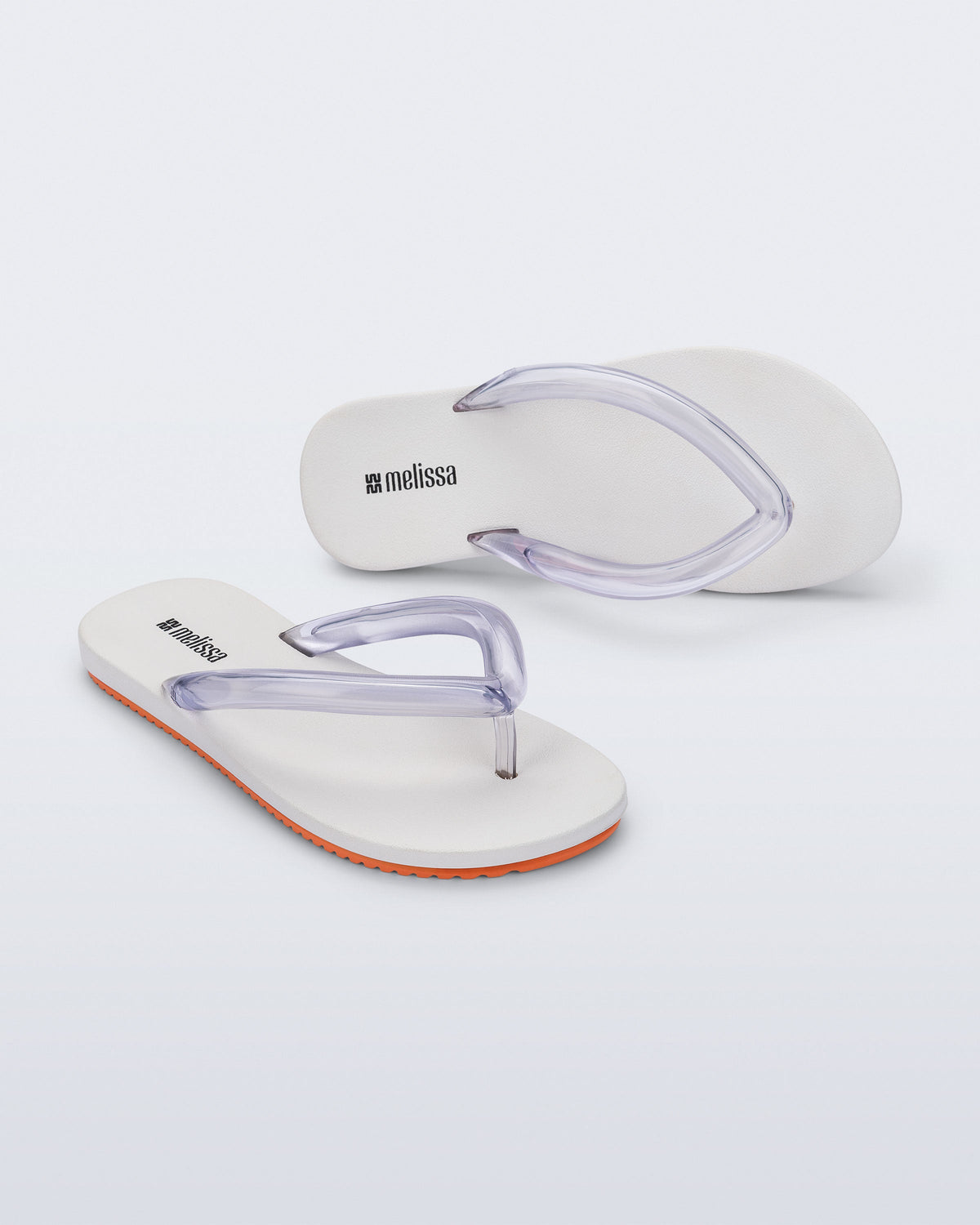 Top and angled view a pair of white Flip Flop Airflow sandal with a clear strap and orange bottom