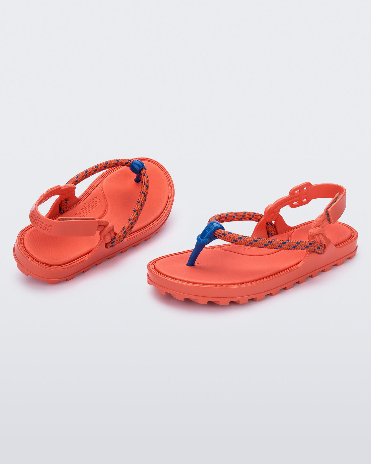 Angled view of a pair of orange Bond sandals with textile strap and blue toe piece