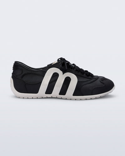 Side view of a black Motion sneaker with white colored sole and M monogram