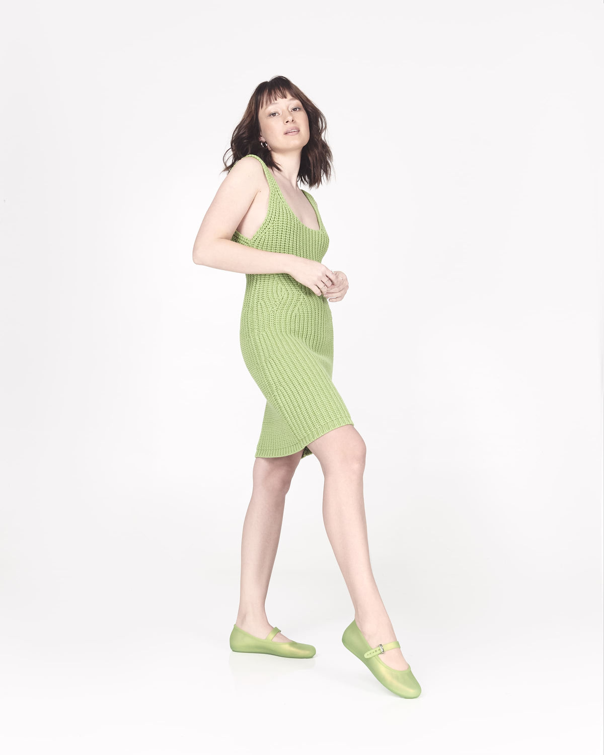 Model in a green outfit wearing a pair of green Soft adult flats with strap and green buckle