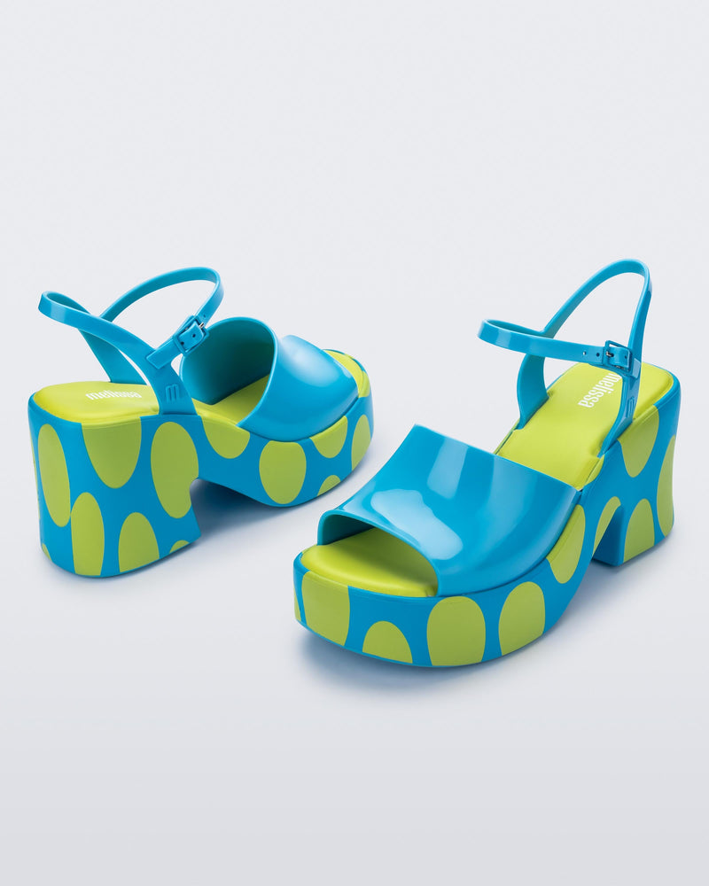 Angled view of a pair of blue with green polka dot sole Lina platform heels