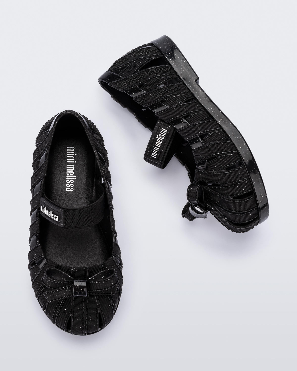 Top and side view of a pair of glitter black M Lover Ballerina baby flat with bow and strap
