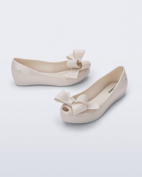 Top and side angled view of a pair of beige Ultragirl Classy kids ballerina flats with beige bow