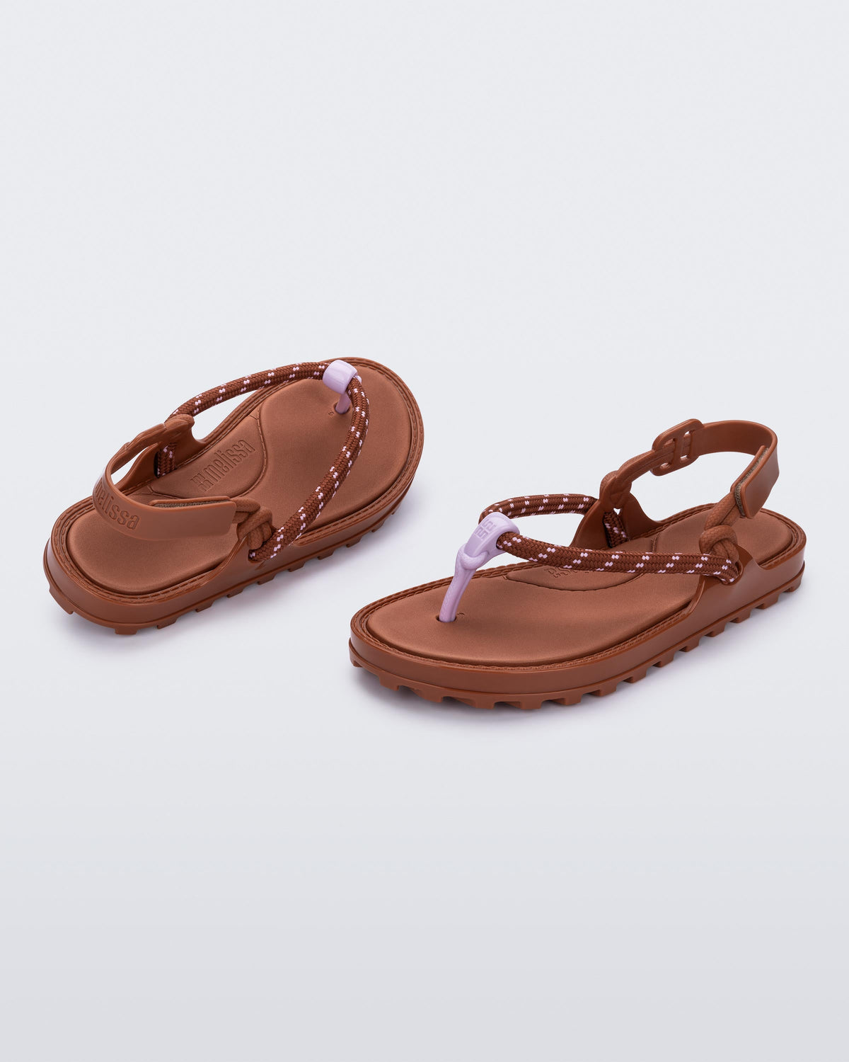 Angled view of a pair of brown Bond sandals with textile strap and purple toe piece