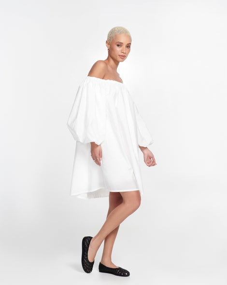 Model in a white dress wearing a pair of black Possession Ballerina flats