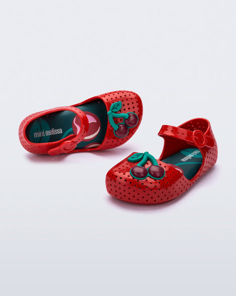 Angled and top view of a pair of red Pop baby flats with two dark red cherries