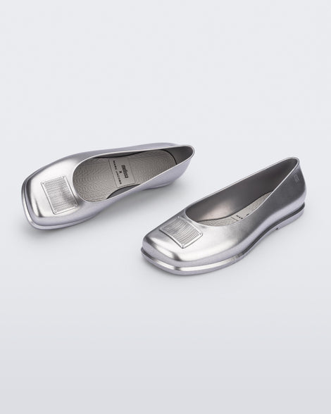 Side and angled view of a pair of metallic silver Ruby + Marc Jacobs flats