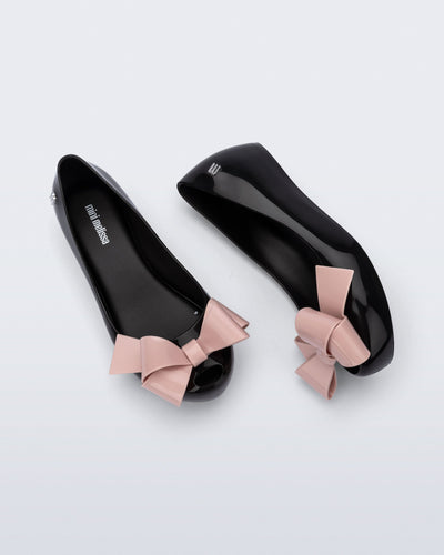 Top and side view of a pair of black Ultragirl Classy kids ballerina flats with pink bow