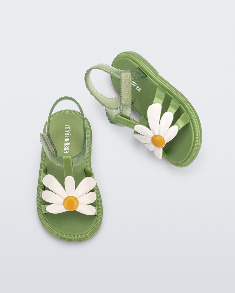 Top and side view of a pair of green baby Hip Bloomy sandal with a white flower