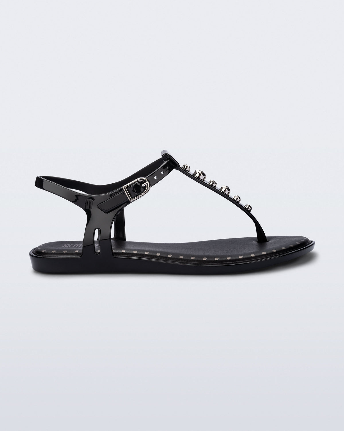 Side view of a black Solar Boho t-strap sandal with ,metallic detailing on the front strap