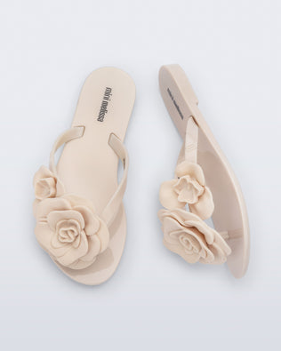 Top and side view of a pair of beige Harmonic Petals kids flip flops with flowers