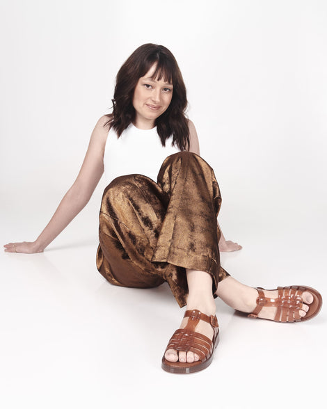 Model in brown pants wearing a pair of transparent brown Possession Fresh fisherman style sandals with open toe.