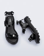 Side and top view of a pair of black Town Bow sandals with bows and a pearl in the center of each bow