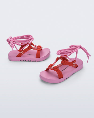 Side and angled view of a pair of pink sole, red upper, and pink ankle strap Kirk + Alexandre Pavao sandals