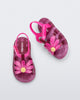 Angled and top view of a pair of glitter pink baby Hip Bloomy sandal with pink straps and flower