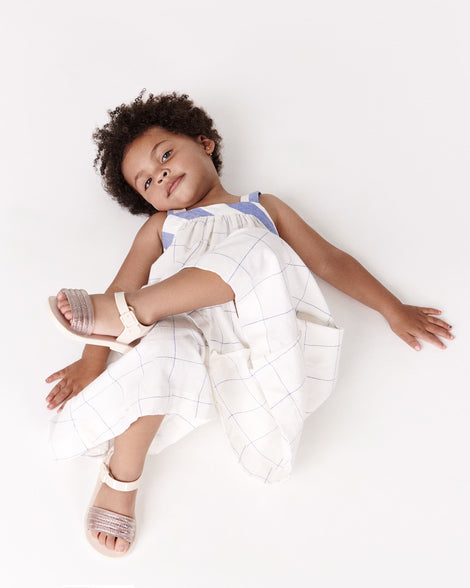 Toddler model in a white and blue outfit wearing a pair of beige Mar Wave baby sandals.