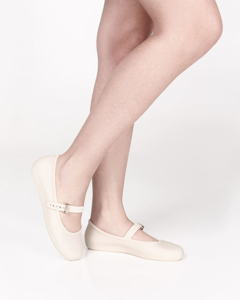 Model's legs wearing a pair of beige Soft adult flats with strap and gold buckle