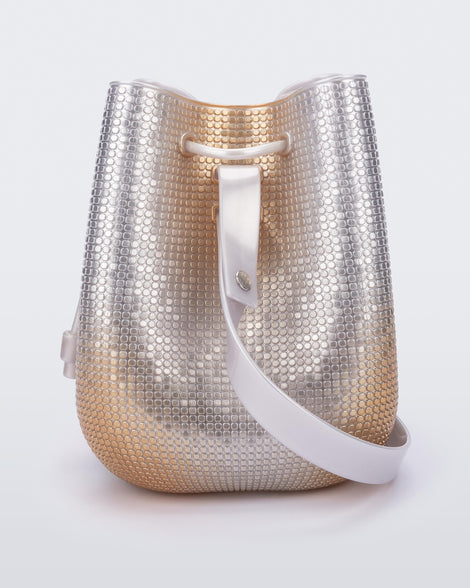 Side view of a silver/gold Lux bucket bag with drawstring and strap