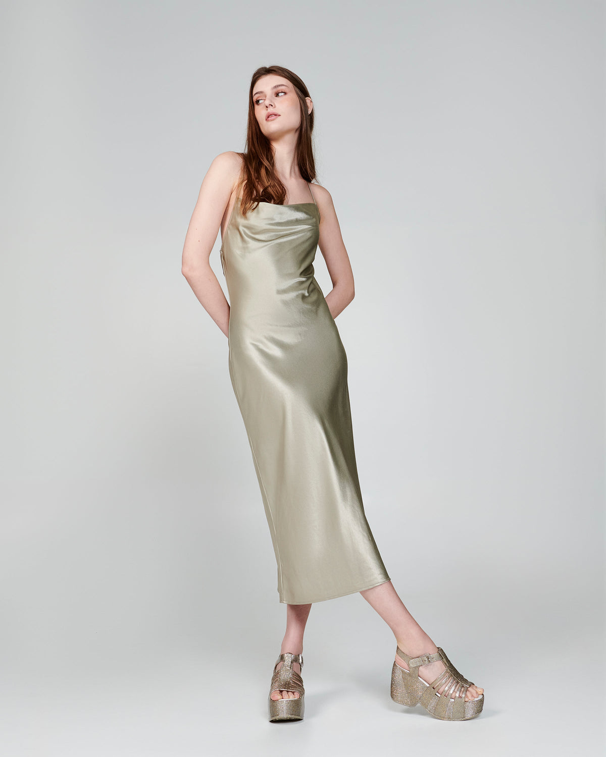 Model in a beige dress wearing a pair of glitter gold Station 79 platform heels with ankle strap