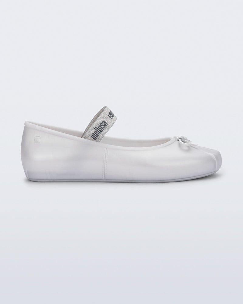 Side view of a pearly white Sophie flat with top elastic strap and small bow