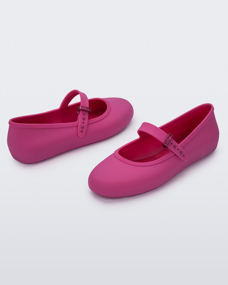 Angled view of a pair of pink Soft adult flats with strap and pink buckle