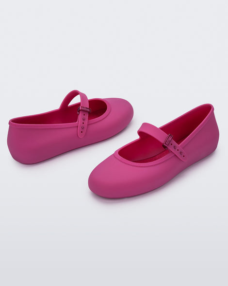 Angled view of a pair of pink Soft adult flats with strap and pink buckle