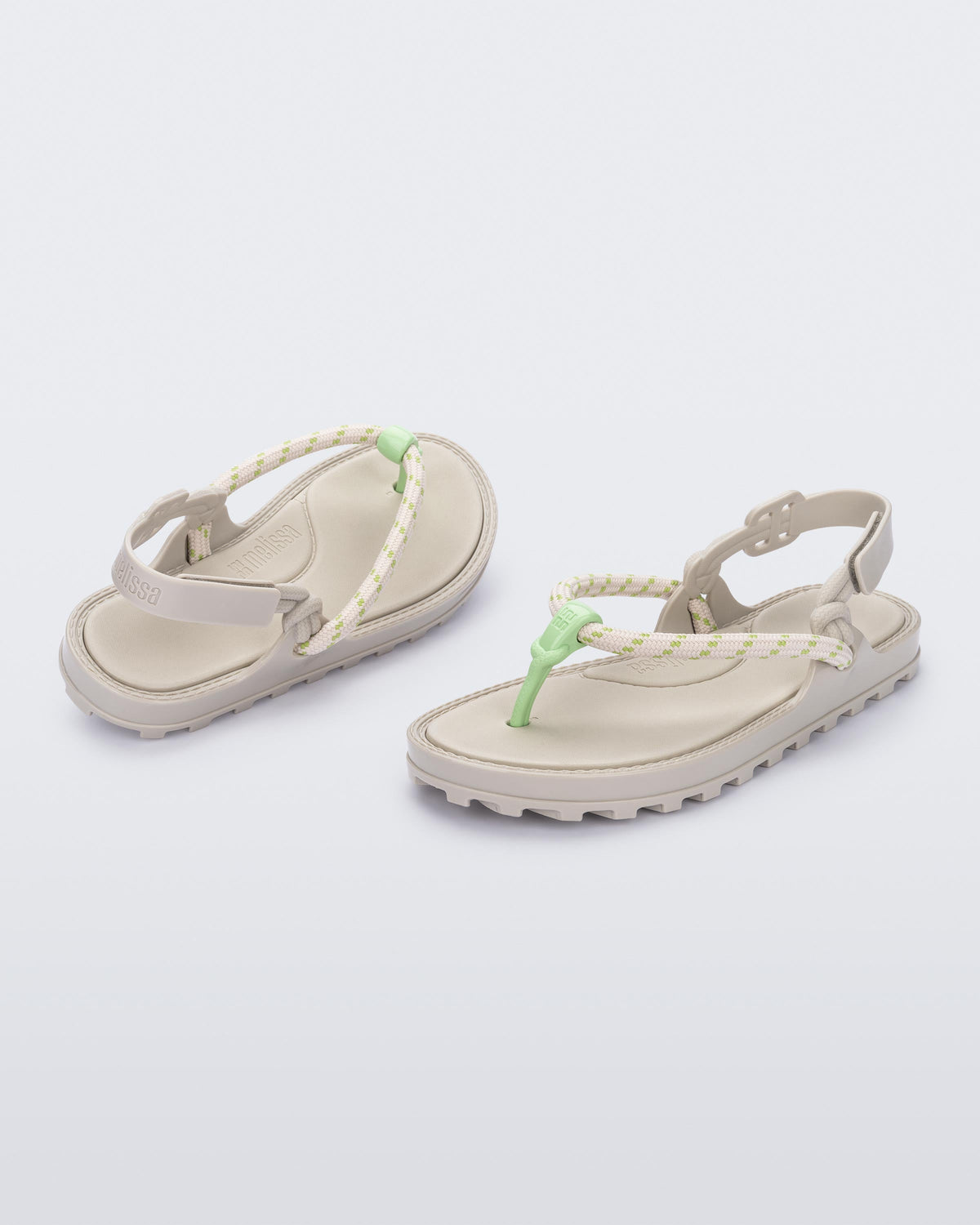Angled view of a pair of beige Bond sandals with textile strap and green toe piece