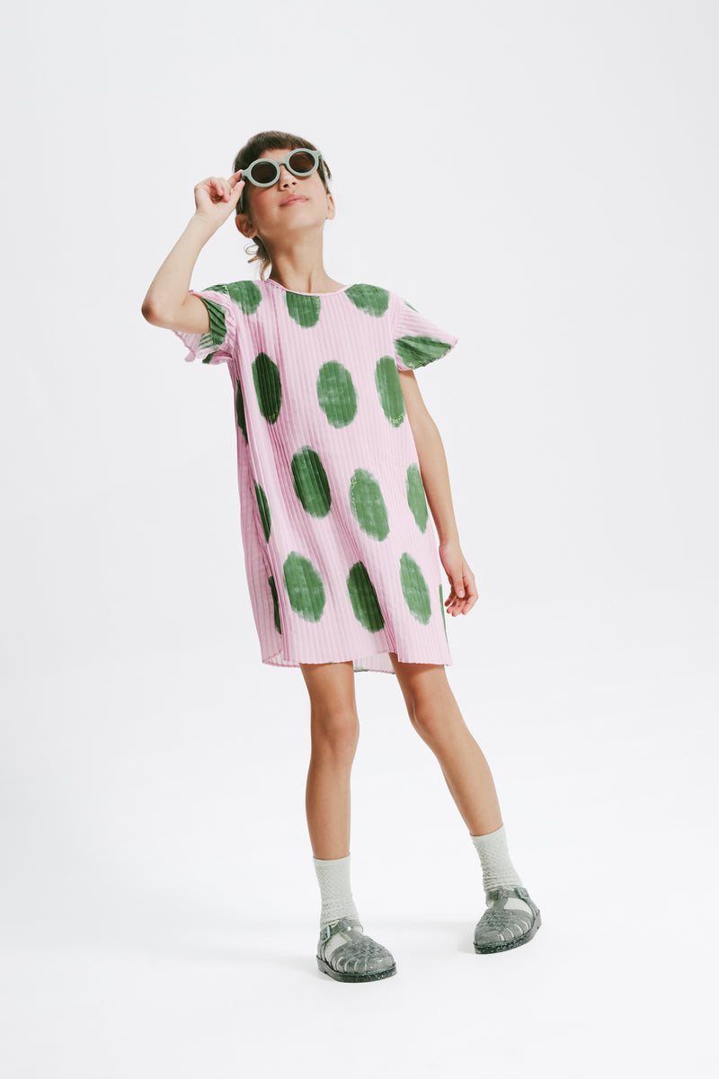Child model in a pink and green dress wearing glitter green Possession kids sandals with green socks