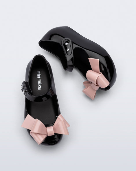 Top and side view of a pair of black Ultragirl Classy baby ballerina flats with pink bow