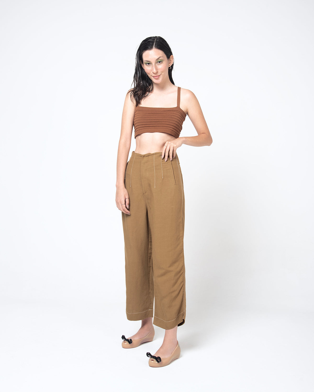 Model in a brown outfit wearing a pair of beige Ultragirl Bow flats with black bow