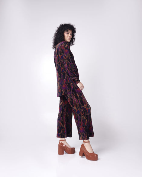 Model in a black patterned pant suit wearing a pair of brown Melissa Doll Heel platforms with ankle strap.