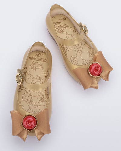 Top view of a pair of beige Sweet Love Snow White baby flats with a beige bow with red apple center