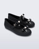 Angled view of a pair of black Soft Ballerina Bow flats with bows and a pearl in the center of each bow